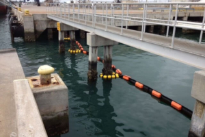 Containment boom tether system on pier